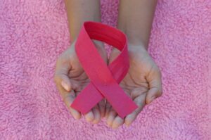Main tenant un ruban rose, symbole de la lutte contre le cancer du sein