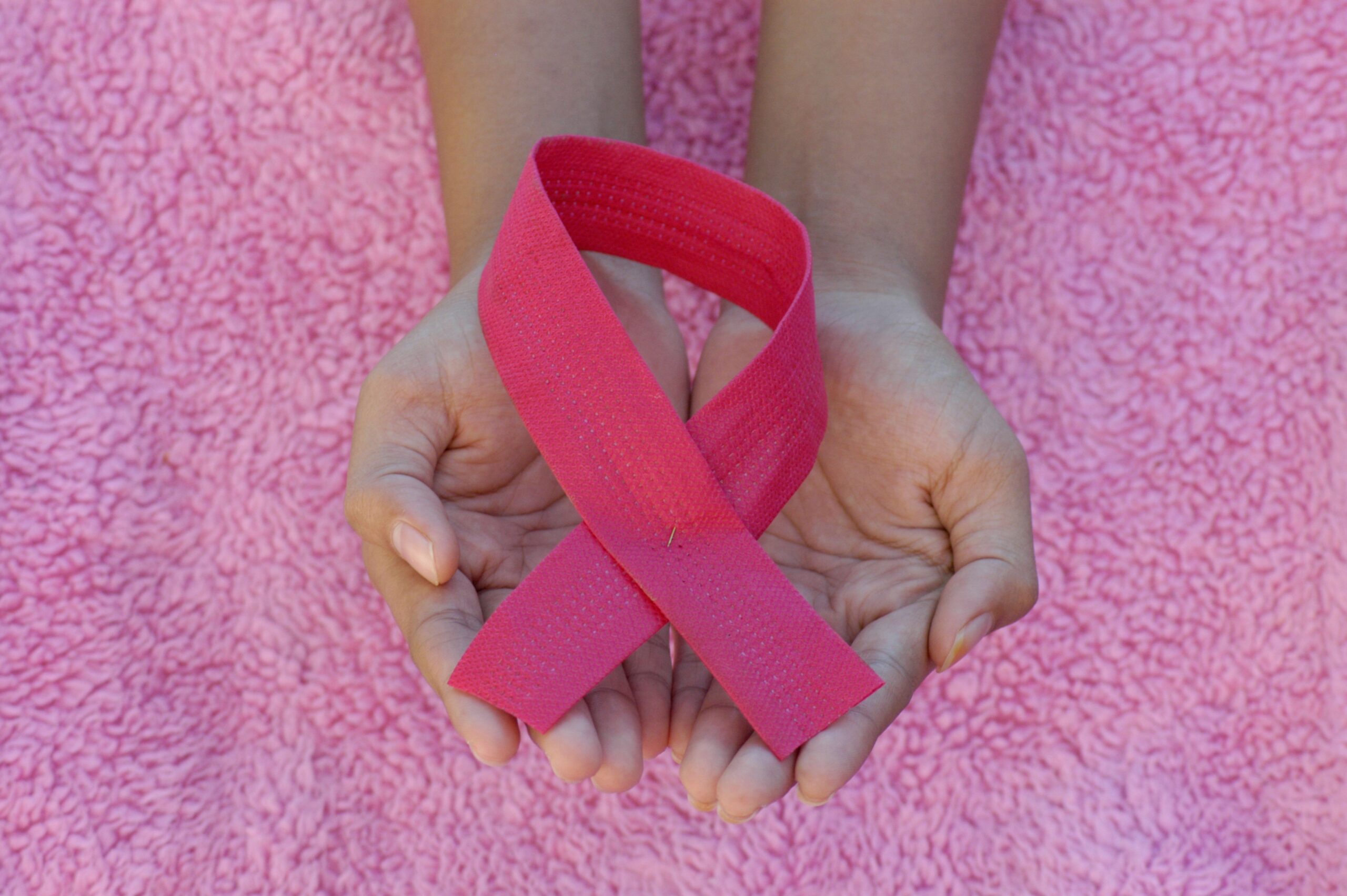 Main tenant un ruban rose, symbole de la lutte contre le cancer du sein